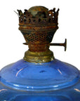 Close-up of antique blue glass oil lamp with rusty metal burner, in very good condition on plain white background.