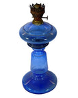 Close-up of antique blue glass oil lamp with round base and metal burner, shown in very good condition.