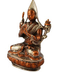 Close-up of brass statue depicting a peaceful, robed deity with pointed hat on an ornate base.
