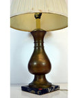 Beige pleated shade brass lamp with a black marble base, close-up against plain background.