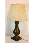 Close-up of brass lamp with pleated beige shade and square marble base, set against a plain background.