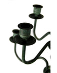 Close-up of bronze candelabra centerpiece with three empty candle cups against a white background.