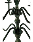 Close-up of bronze candelabra with curved arms and greenish weathered patina on centerpiece.
