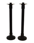 Close-up of two tall black bronze candle holders with round bases and ribbed accents, side by side.