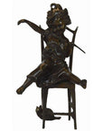 Bronze doll of a playful child sitting on chair with a cat in their lap and another cat beside the chair.
