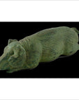 Bronze pig sculpture lying on its side against a solid black background, tabletop decor close-up.