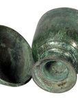 Green bronze urns with aged patina, lying on their sides, showing weathered surfaces.