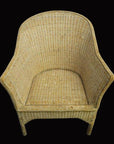 Natural rattan Burmese chair with curved back and sides on solid black background.