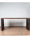 Dark wood Burmese vintage waterfall console table with scrolling feet against a white brick wall.