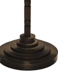 Close-up of a bronze-colored metal candle holder with tiered, geometric ridged design and modern vertical stem.