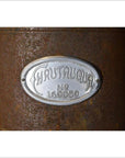 Close-up of a metal Chautauqua oil and kerosene stove plaque with “Chautauqua No. 169050” on a rusty surface.