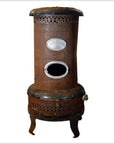 Black metal vintage Chautauqua oil and kerosene stove with oval opening and three curved legs, close-up view.