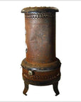 Rusty metal Chautauqua oil kerosene stove, cylindrical with perforations, three short legs, close-up view.