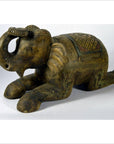 Brown wooden Chiang Mai hand carved elephant figurine with ornate carvings, close-up on plain background.