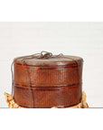 Brown wood Chinese tiered food basket with stacking parts and lid on crumpled paper, white background.