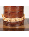 Close-up of a brown Chinese 19th century tiered food basket with stacking parts and paper, on a wooden surface.