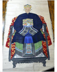 Close-up of Chinese ancestor painting on linen canvas with gold leaf accents, elder seated on red embroidered cloth.