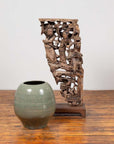 Green ceramic vase and Chinese antique 1900s hand carved wood corbel with deities on wooden floor.