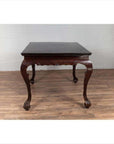 Black lacquered wood hall table with cabriole legs, positioned indoors against a white wall.