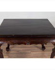 Black lacquered wood center hall table with cabriole legs on wooden floor against a white wall indoors.