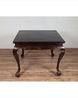 Black lacquered wood hall table with cabriole legs on wood floor against a white brick wall indoors.