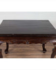 Black lacquered wood hall table with cabriole legs on wooden floor against a white brick wall indoors.