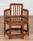 Brown bamboo corner chair with hexagonal base on wooden floor next to a white brick wall indoors.