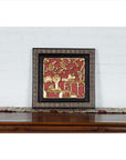 Red and gold giltwood Chinese antique floral architectural panel on wooden table.