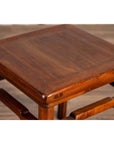 Close-up of brown wood Chinese Ming style side table with humpback stretcher on a wooden floor.