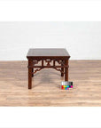Dark wood Chinese antique side table with open fretwork design, on wooden floor, color card in front.