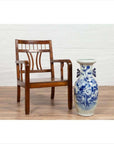 Brown elmwood Chinese Art Deco armchair with pierced and curved design beside white and blue ceramic vase on wood floor.