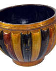 Close-up of a round bamboo rice basket with gold, brown, and black stripes, ribbed texture, and cracked glossy finish.