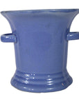 Close-up of blue celadon ceramic planter with flared rim and side handles on a white background.