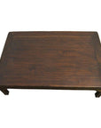 Rectangular dark wood Chinese coffee table with carved friezes and four legs on a white background.