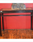 Red Chinese console table with pudding stone inset, positioned against a red wall on a wooden floor.