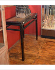 Black wood Chinese console table with decorative items, positioned on a wooden floor between glass display cabinets.