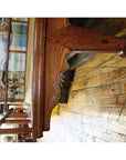 Dark wood Chinese daybed with ornate legs on a worn wooden floor, murals and windows in the background indoors.