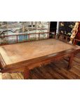 Brown wooden Chinese daybed with woven rattan surface on wood floor, decorative panels in the background.