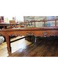 Dark wood Chinese daybed with carved floral sides, set on a wooden floor inside an antique store.