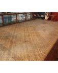 Brown wooden Chinese daybed with woven bamboo or rattan seat and decorative backrest, indoors.