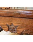 Close-up of dark wood Chinese daybed edge with ornate carvings and a small metal hinge.