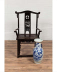 Dark patina Chinese elmwood Dengguayi scholar's chair behind tall blue-and-white porcelain vase on wood floor.