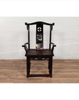 Dark patina Chinese elmwood Dengguayi scholar's chair on wood floor against white brick wall, color chart on seat.