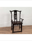 Dark patina Chinese elmwood Dengguayi scholar's chair on wooden floor with white brick wall background.