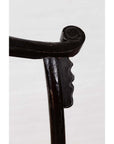 Close-up of dark Chinese elmwood armrest with curved notched design, Dengguayi Scholar's Chair, on light background.
