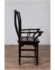 Dark wood Chinese elm chair, side view, on wooden floor with white brick wall in background.