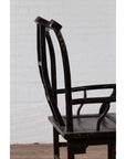 Dark wood Chinese elm chair, side view, on wooden floor with white brick wall background.