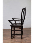 Dark patina elmwood chair side view on wood floor, white brick wall background.