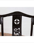 Close-up of dark Chinese elmwood chair with intricate floral and dragon carvings.
