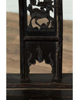Close-up of dark elmwood chair with dragon carvings and decorative cutouts.